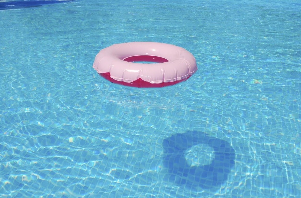 Pink pool float in perfectly balanced crystal clear blue pool water in Paramount, CA